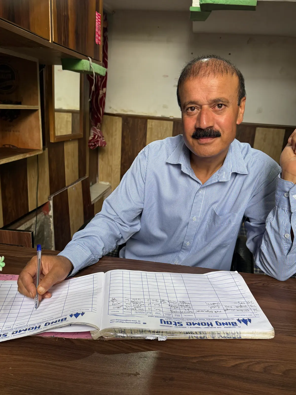Rafiq at the front desk, writing in the Bing Homestay guest register